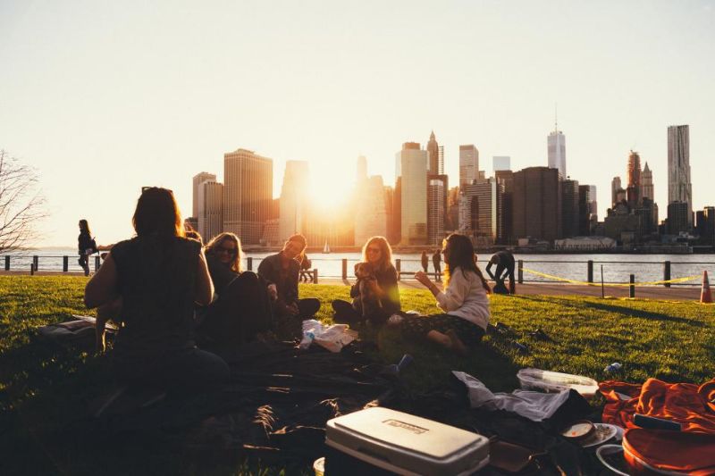 Friends picnicking together in a park at golden hour.